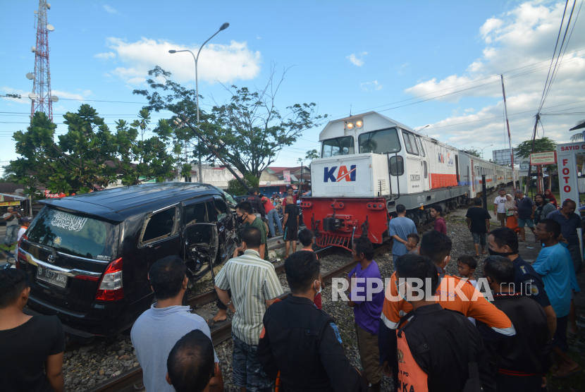 Warga melihat kondisi mobil yang tertabrak Kereta Api (KA) Sibinuang jurusan Naras - Padang di Lubuk Buaya, Padang, Sumatera Barat,  Ahad (2/5/2021). Akibat kejadian tersebut pengemudi mobil mengalami luka-luka serta terganggunya jadwal keberangkatan kereta, sementara itu PT KAI Divre II Sumbar mencatat sedikitnya 15 kasus kecelakaan terjadi pada awal 2021 di perlintasan sebidang rel kereta api. 
