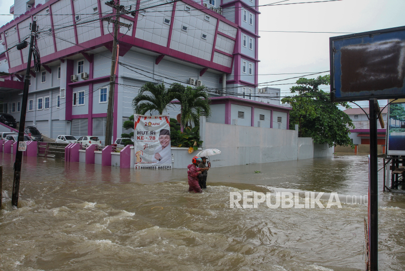 Warga melintasi jalan yang terendam banjir di Pekanbaru, Riau (ilustrasi). 