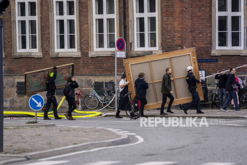 Orang-orang membawa lukisan bersejarah dari Bursa Efek lama (Boersen) setelah kebakaran melanda gedung tersebut, di Kopenhagen, Denmark, (16/4/2024).
