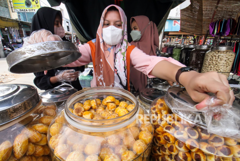 Pedagang kue kering melayani pembeli. Kios-kios kue di Pasar Jatinegara, Jakarta Timur memasuki hari ke-22 puasa Ramadhan mulai ramai pengunjung yang berburu beragam camilan untuk disajikan saat Hari Raya Idul Fitri 1444 H, dengan jenis kue nastar dan putri salju yang paling digemari konsumen./ilustrasi