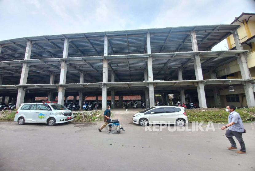 Warga melintas di depan lokasi pembangunan gedung poliklinik RSUD dr Soekardjo, Kota Tasikmalaya, Jawa Barat, Kamis (26/1/2023). Proyek pembangunan gedung tiga lantai itu mandek selama setahun terakhir. 