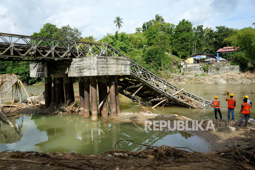 Sejumlah pekerja melihat kondisi jembatan Molintogupo yang ambruk diterjang banjir bandang di Alale, Kabupaten Bone Bolango, Gorontalo, Ahad (14/6/2020). Sebanyak 12 ribu warga dari tujuh kecamatan di Bone Bolango menjadi korban banjir.