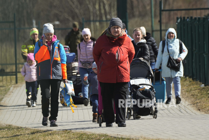 Pengungsi berjalan di perbatasan di Medyka, Polandia tenggara, setelah melarikan diri dari perang dari negara tetangga Ukraina, Ahad 27 Maret 2022.