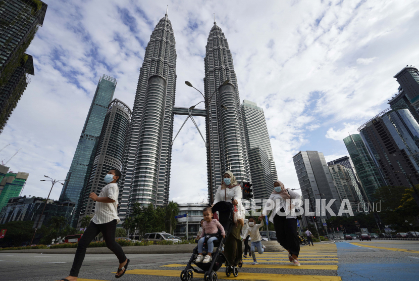 Sebuah keluarga yang memakai masker wajah berjalan di depan Menara Kembar di pusat kota Kuala Lumpur, Malaysia. Mulai 1 Maret 2021. sekolah tatap muka di Malaysia dimulai kembali.