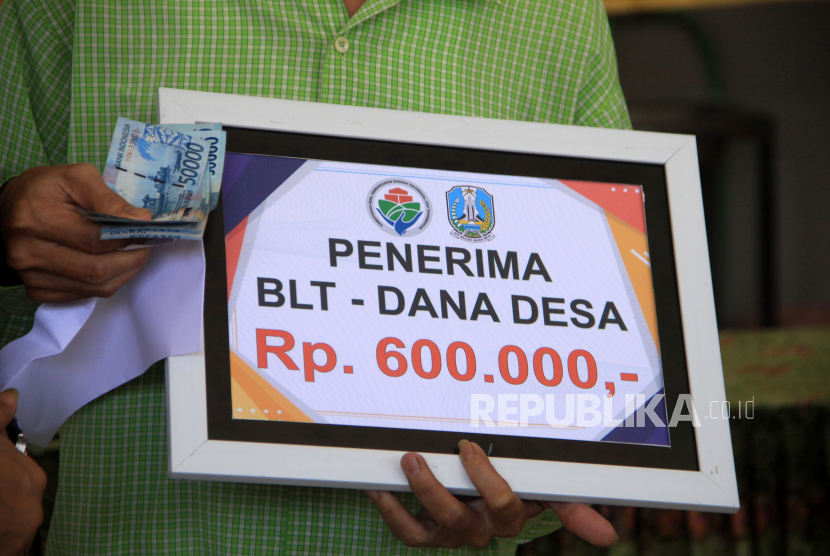 Warga menerima uang Bantuan Langsung Tunai (BLT) dana desa di Balai desa Berbek, Waru, Sidoarjo, Jawa Timur, Ahad (17/5) lalu. Bantuan Langsung Tunai Dana Desa (BLT-DD) telah disalurkan oleh 23.963 desa kepada keluarga penerima manfaat (KPM).