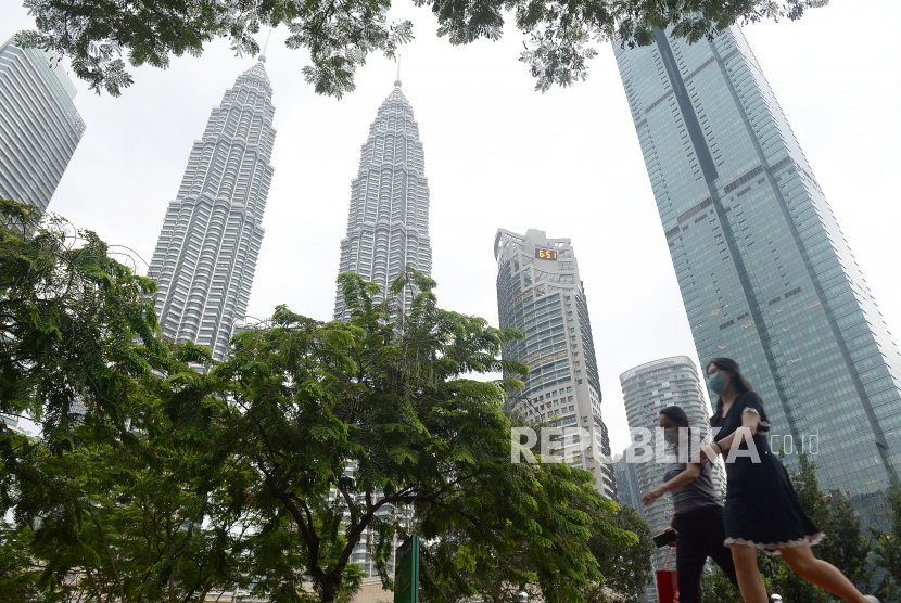 Sejumlah warga berjalan di taman kawasan Menara Berkembar Petronas (KLCC) di Kuala Lumpur, Malaysia.