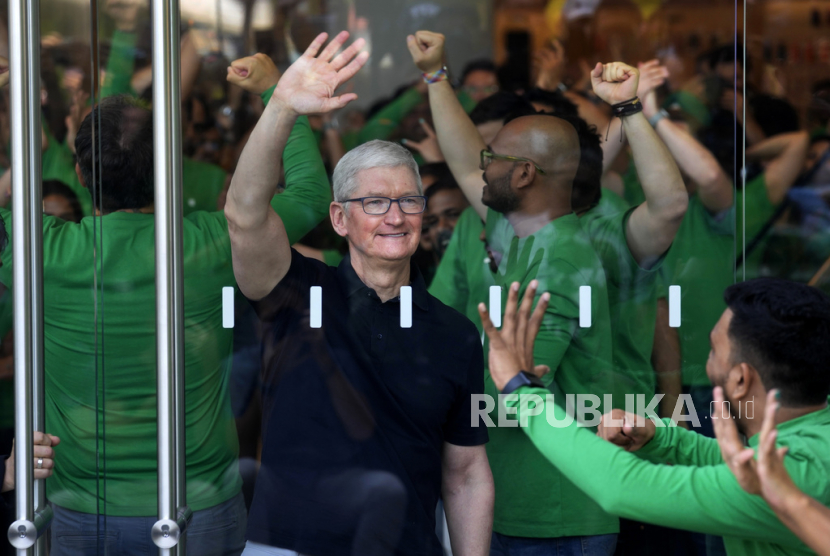 Apple CEO Tim Cook melambaikan tangan kepada puluhan orang yang menunggu di luar saat pembukaan toko Apple Inc perdana di Mumbai, India. Penjualan Apple terus turun, karena ekonomi melambat dan lemahnya daya beli akibat kenaikan harga yang membuat konsumen menunda pembelian komputer dan iPad.