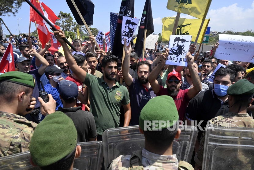 Tentara Lebanon berjaga-jaga ketika para pendukung Hizbullah meneriakkan slogan-slogan selama protes menentang kunjungan Komandan Komando Pusat Angkatan Darat AS, Kenneth Franklin McKenzie ke Lebanon di jalan raya bandara internasional Rafic Hariri di Beirut, Lebanon, 08 Juli 2020. 