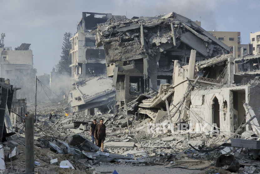 Warga Palestina berjalan melewati puing-puing bangunan yang hancur akibat serangan udara Israel di Kota Gaza pada Rabu, (11/10/2023)WIB.