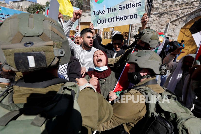  Seorang wanita Palestina meneriakkan slogan di depan pasukan Israel selama protes terhadap pemukim Israel, di Hebron, di Tepi Barat, yang diduduki Israel pada 26 Februari 2021.