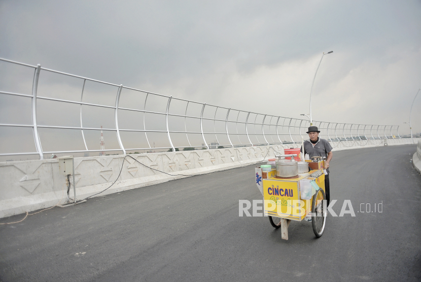 Pedagang melintas di area pembangunanan jalan layang Cakung di Jakarta Timur, Selasa (16/3).  Republika/Thoudy Badai