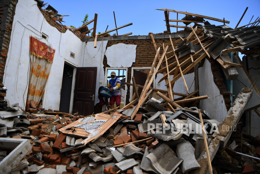 Seorang warga mengamankan barang berharga miliknya di antara reruntuhan rumahnya di Kabupaten Malang, Jawa Timur.