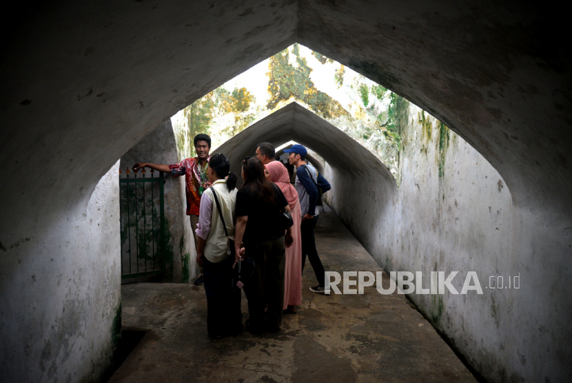 Pemandu menjelaskan sejarah bangunan kepada wisatawan saat berjalan-jalan di kawasan Tamansari, Yogyakarta.