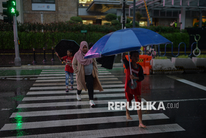 Ojek payung menjajakan jasa sewa payung saat hujan di kawasan Halte MRT Bundaran HI, Jakarta, Jumat (23/5/2025). 
