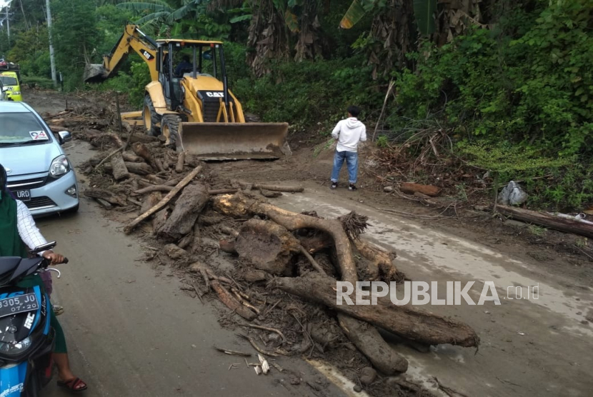 Alat berat membersihkan material kayu akibat banjir bandang yang menutupi jalan Trans Sulawesi. (Ilustrasi)