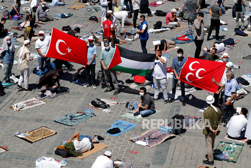  Orang-orang memegang bendera Turki dan Palestina ketika mereka menunggu shalat Jumat di luar Masjid Agung Hagia Sophia, untuk pertama kalinya setelah sekali lagi dinyatakan sebagai masjid setelah 86 tahun, di Istanbul, Turki, 24 Juli 2020. 