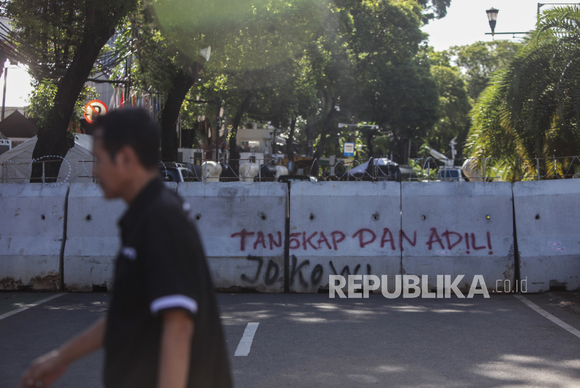 Warga berjalan di dekat pembatas jalan menuju Gedung KPU di Jalan Imam Bonjol, Jakarta, Selasa (19/3/2024). Jelang hasil akhir proses rekapitulasi nasional Pemilu 2024 akses menuju Gedung KPU ditutup untuk peningkatan keamanan.
