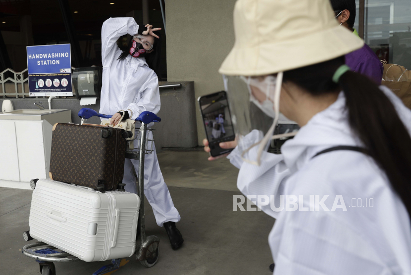  Penumpang asing yang mengenakan pakaian pelindung memeriksa barang-barang mereka saat mereka bersiap untuk penerbangan mereka ke China di Bandara Internasional Manila, Filipina, Senin, 18 Januari 2021.