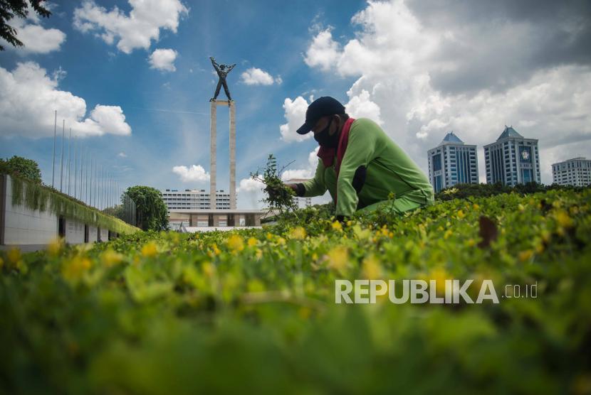 Pekerja beraktivitas di area Taman Lapangan Banteng dengan latar belakang lanskap langit berwarna biru di Jakarta. Cuaca DKI Jakarta Malam Ini Hingga Kamis Pagi