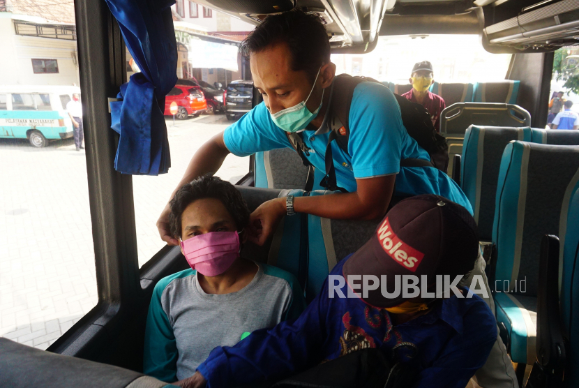 Petugas membantu penderita gangguan jiwa (ODGJ) mengenakan masker saat menunggu pemberangkatan bus yang akan mengangkutnya ke RSJ Menur, di halaman kantor Dinas Kesehatan Tulungagung, Tulungagung, Jawa Timur, Senin (31/8/2020). Sebanyak 15 ODGJ dibawa ke Rumah Sakit Jiwa (RSJ) Menur, Surabaya guna mendapat perawatan lanjutan dalam rangka penuntasan program Indonesia Bebas Pasung 2020 di Tulungagung. 