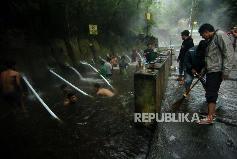 Petugas dibantu warga membersihkan tempat pemandian air panas pancuran 13 di Obyek Wisata Guci, Kabupaten Tegal, Jawa Tengah, Sabtu (25/2/2023). Tempat pemandian air panas pancuran 13 penuh ditutup sementara akibat penuh pasir dan sejumlah pipa rusak sehingga suplai air bersih di tempat penginapan terhambat pasca banjir bandang Jumat (24/2/2023) malam.