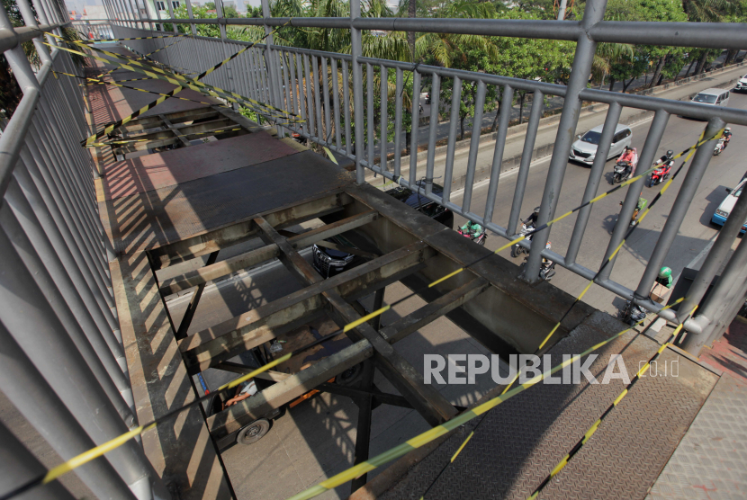 Petugas memeriksa  jembatan penyeberangan orang (JPO) Sahabat yang berlubang akibat pelat besi dicuri di Jalan Daan Mogot, Jakarta Barat, Jumat (4/8/2023). 