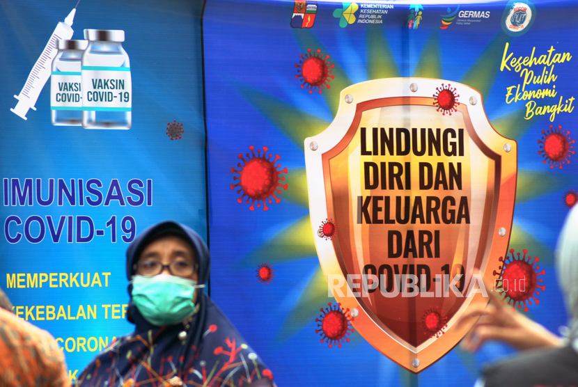 Warga melewati baliho sosialisasi vaksinasi COVID-19 di Kota Bogor, Jawa Barat.