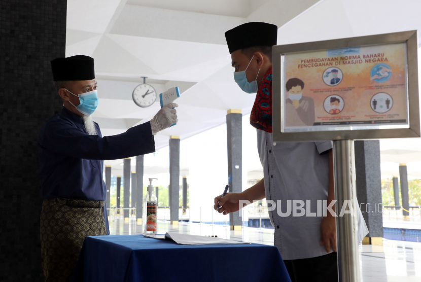 Raja Perlis Malaysia Minta Pengurus Masjid Perketat Protokol. Petugas mengukur suhu seorang pria di pintu masuk Masjid Nasional, Kuala Lumpur, Malaysia. Ilustrasi
