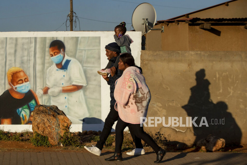 Warga berjalan melewati mural bergambar vaksinasi Covid-19 di kotapraja Duduza, Afrika Selatan, Rabu (23/6).  Afrika Selatan mencabut pembatasan pergerakan orang antarprovinsi ketika gelombang ketiga virus corona telah mencapai puncaknya.