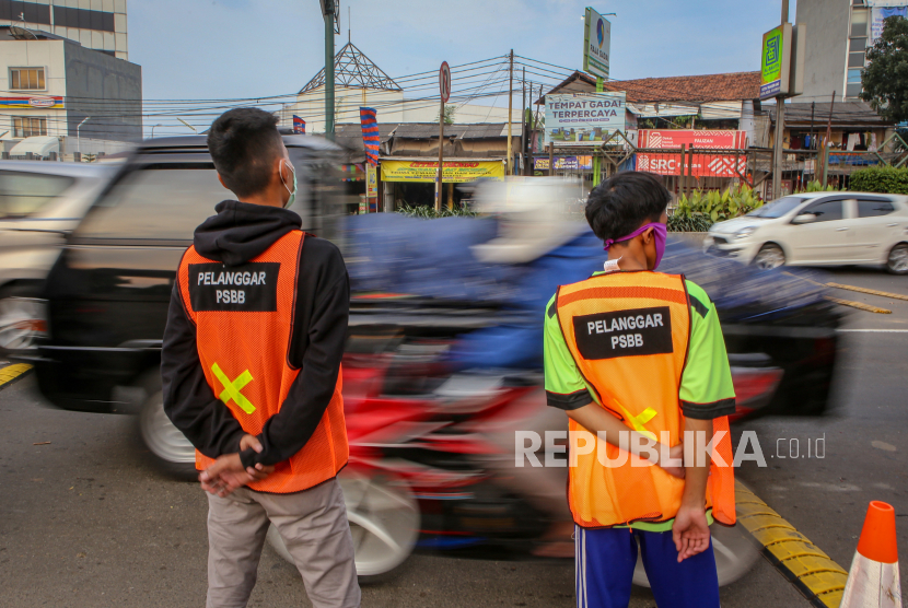 Dua orang warga pelanggar PSBB membantu petugas mengatur lalu lintas di di Jalan M.H Thamrin, Kota Tangerang, Banten, Ahad (17/5/2020)