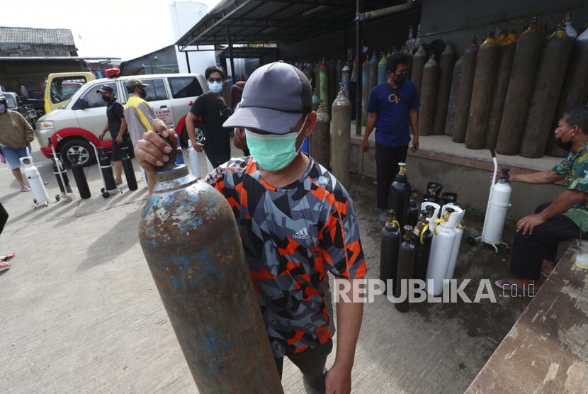 Seorang pria memegang tangki setelah mengisi ulang oksigennya di sebuah stasiun pengisian bahan bakar di Jakarta, Indonesia, Sabtu, 10 Juli 2021.
