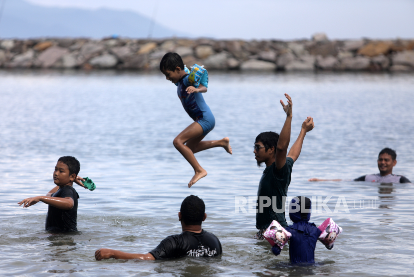 Anak-anak berenang di pantai.