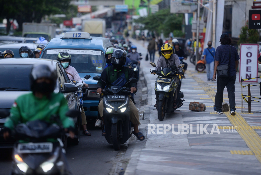 Pengendara motor berjalan melewati trotoar untuk menghindari kemacetan di Jalan Raya Margonda, Depok. Komika Rais kritik rencana Pemkot Depok menata trotoar Margonda sebesar Rp 18 miliar.
