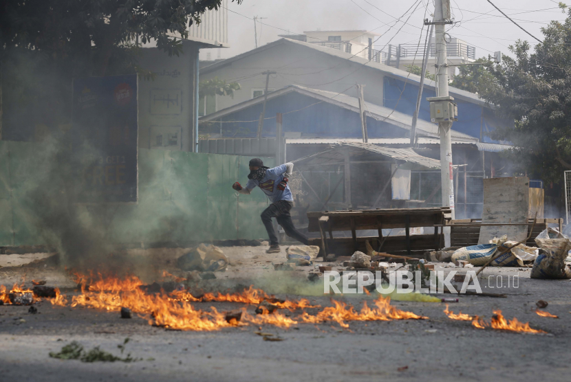  Seorang pria berlari melewati barikade jalan dan membakar puing-puing pada Senin, 22 Maret 2021, di Mandalay, Myanmar. 