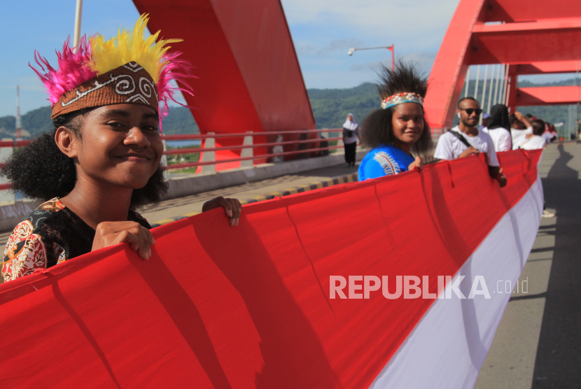 Siswa SMP membentangkan Bendera Merah Putih di  Jembatan Youtefa Holtekamp, Kota Jayapura, Papua, Rabu (1/5/2024). Pemerintah meluncurkan RIPPP untuk mempercepat pembangunan Papua.