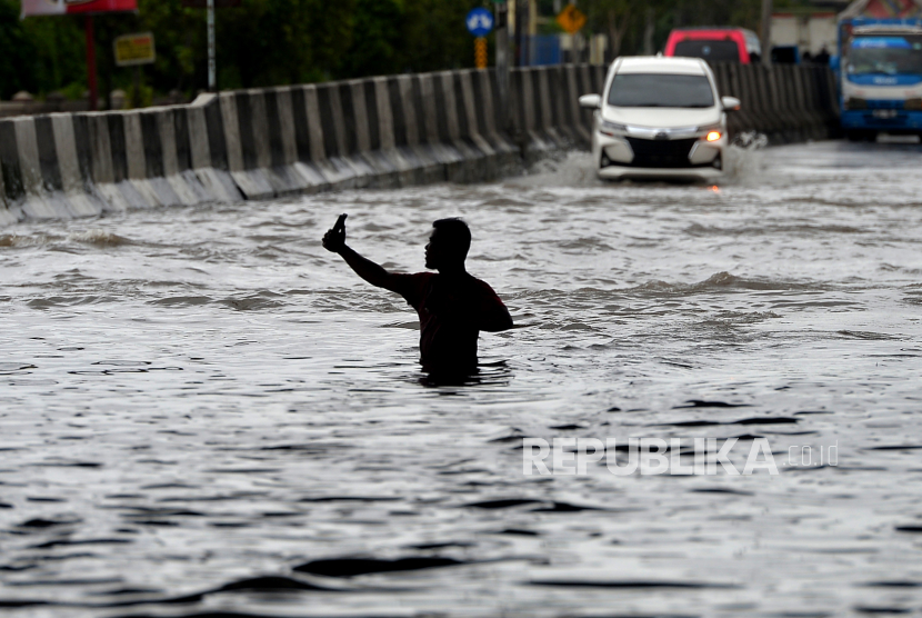 Warga berswafoto saat banjir di Kawasan Kaligawe, Semarang, Jawa Tengah, Senin (2/1/2023). Tingginya curah hujan di Semarang menyebabkan ruas jalan raya Semarang-Demak terganggu. Saat ini hanya bisa dilewati oleh kendaraan besar.