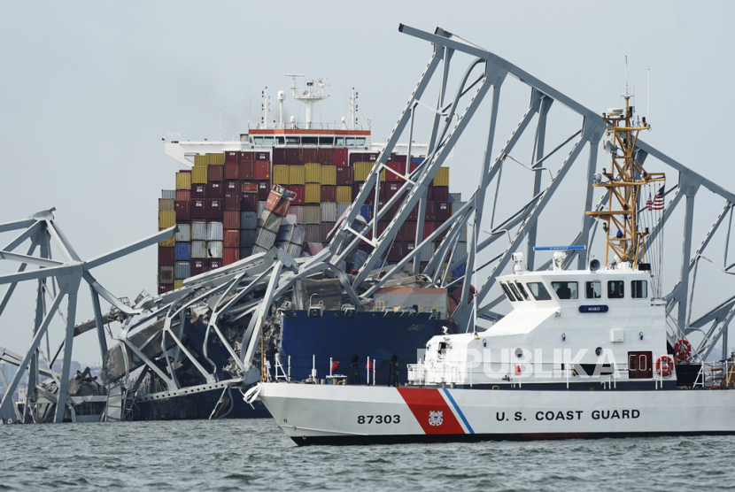 Penjaga Pantai melewati kapal kargo yang terjebak di bawah bagian struktur Jembatan Francis Scott Key setelah kapal tersebut menabrak jembatan di Baltimore, Selasa (26/3/2024).
