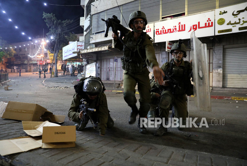 Israeli troops are seen during clashes with Palestinian protesters in the city center of the West Bank city of Hebron, 11 May 2021. Clashes continue over the forced eviction of six Palestinian families from their homes in Sheikh Jarrah neighborhood in favor of Jewish families who claimed they used to live in the houses before fleeing in the 1948 war that led to the creation of Israel. In response to days of violent confrontations between Israeli security forces and Palestinians in Jerusalem, various Palestinian militants factions in Gaza launched rocket attacks on 10 and 11 May that killed three Israelis. Israel Defense Forces (IDF) said they hit over 100 targets in Gaza Strip during the 10 May retaliatory overnight strikes. The Health Ministry of Gaza strip said that at least 26 Palestinian, including nine children, were killed from the Israeli airstrikes. Israeli Prime Minister Benjamin Netanyahu said on 11 May that they will increase the rate and intensity of the strikes. 