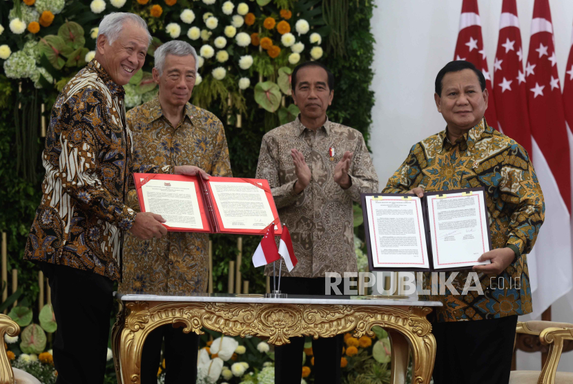  Indonesian Defence Minister Prabowo Subianto (R) and his Singaporean counterpart Ng Eng Hen (L) show agreement books after a signing ceremony witnessed by Indonesian President Joko Widodo (2-R) and Singapore Prime Minister Lee Hsien Loong (2-L) during the Singapore-Indonesia Leaders