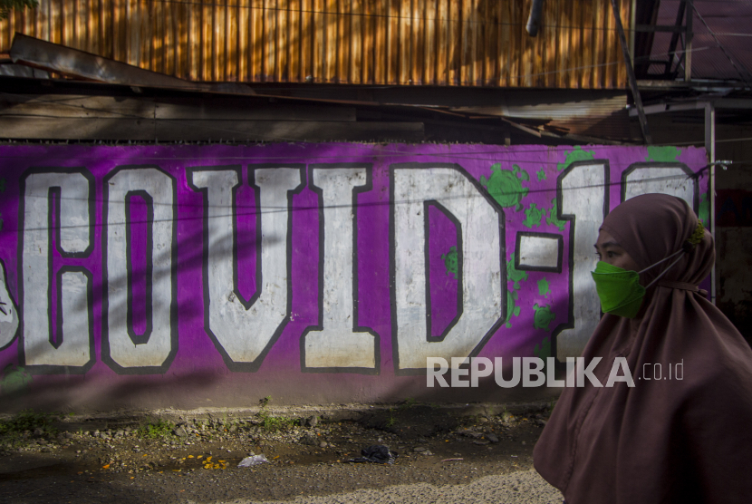 Seorang warga melintas di dekat mural bertema COVID-19 di Banjarmasin, Kalimantan Selatan. Untuk menghindari lonjakan kasus Covid-19 masyarakat diminta tidak berkerumun.