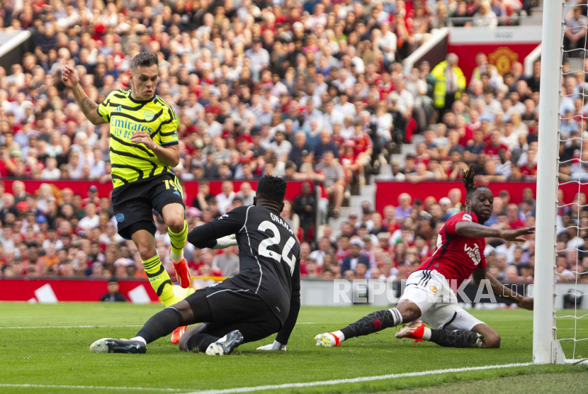   Leandro Trossard of Arsenal (L) scores the 0-1 goal against goalkeeper Andre Onana of Manchester United (C) during the English Premier League soccer match between Manchester United and Arsenal in Manchester, Britain, 12 May 2024.  