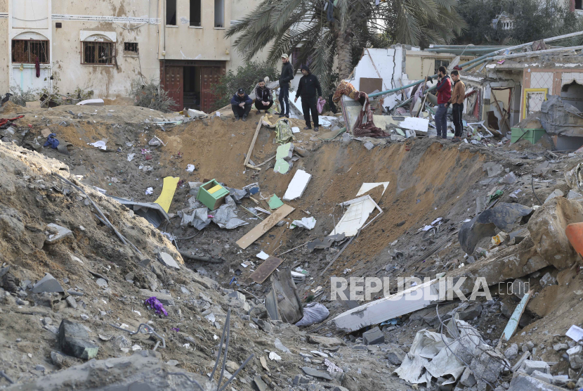 Warga Palestina sedang memeriksa kondisi bangunan yang rusak akibat serangan Israel di Rafah, Jalur Gaza