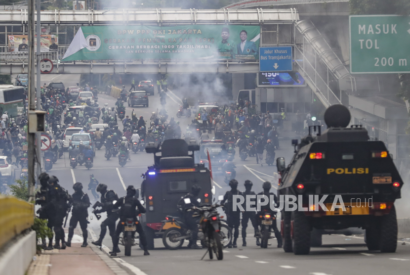 Aparat polisi menggunakan gas air mata untuk membubarkan pengunjuk rasa selama demonstrasi di luar gedung parlemen di Jakarta, Indonesia, 11 April 2022. 