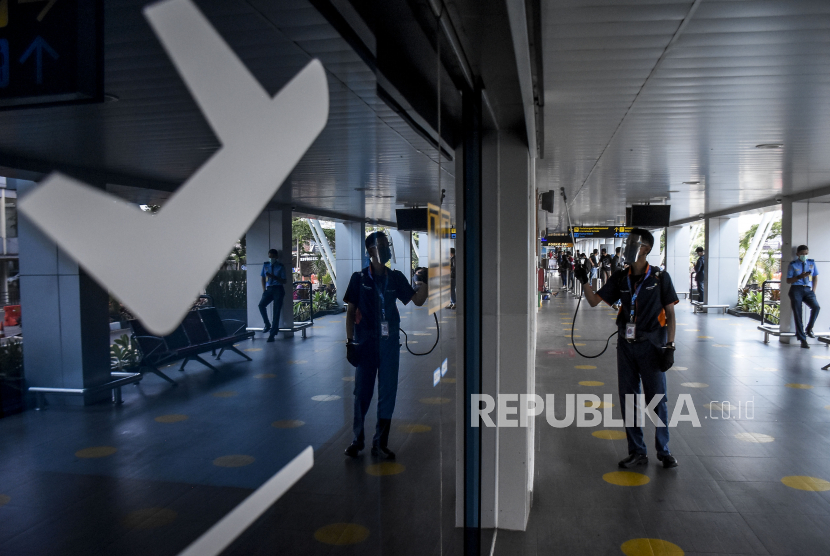 Petugas menyemprotkan cairan disinfektan di area Bandara Husein Sastranegara, Kota Bandung, Ahad (13/12). Kota Bandung masih pertimbangkan rapid test bagi wisatawan.