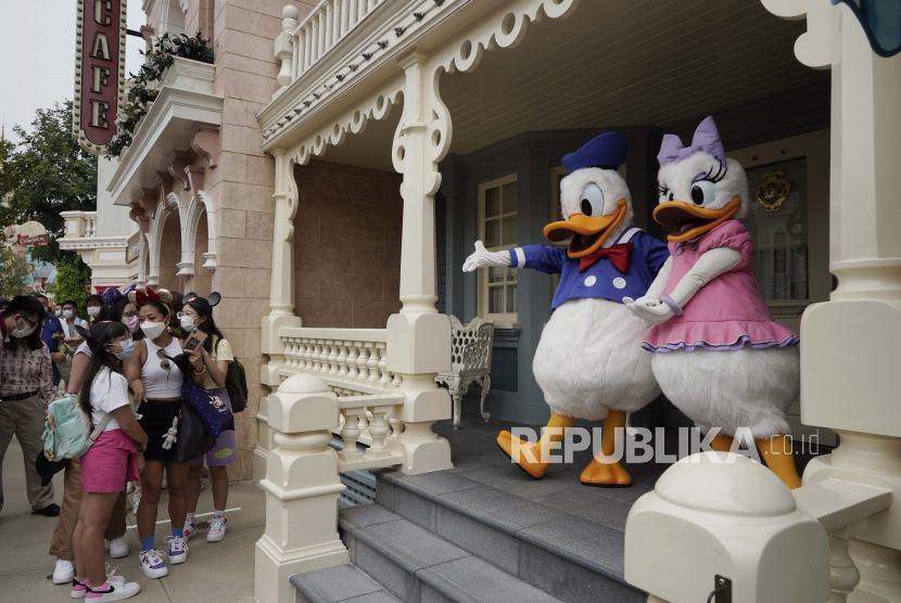 Pengunjung dengan memakai masker mengamati karakter Donald Duck dan Daisy Duck di Hong Kong Disneyland, Jumat (25/9). Hong Kong Disneyland kembali dibuka untuk pengunjung setelah sempat ditutup sementara karena pandemi Covid-19. Foto AP / Kin CheungGaleri Foto