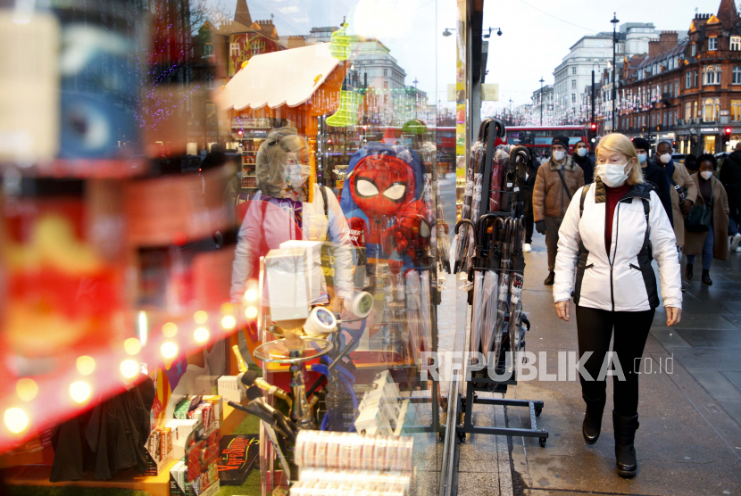  Seorang wanita mengenakan masker wajah untuk berjaga-jaga terhadap COVID-19 berjalan melewati toko suvenir wisata di Oxford Street di London, Senin, 27 Desember 2021. Inggris melaporkan 183.037 kasus infeksi Covid-19. 