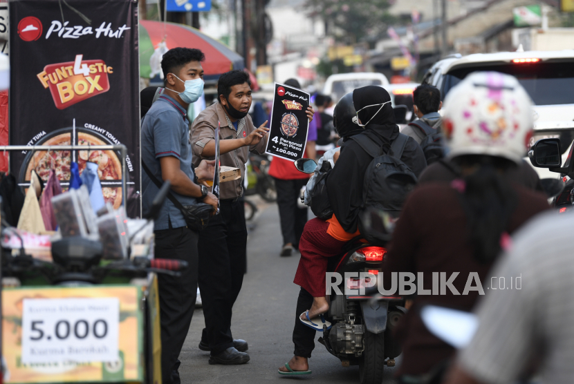Karyawan salah satu gerai pizza menawarkan produk kepada warga yang melintas di Pondok Betung, Tangerang Selatan, Banten, Rabu (13/5/2020). Ditutupnya sejumlah gerai yang berada di pusat-pusat perbelanjaan imbas dari Pembatasan Sosial Berskala Besar (PSBB), disiasati oleh restoran pizza tersebut dengan melakukan aksi jemput bola ke konsumen sebagai upaya bertahan di tengah pandemi COVID-19