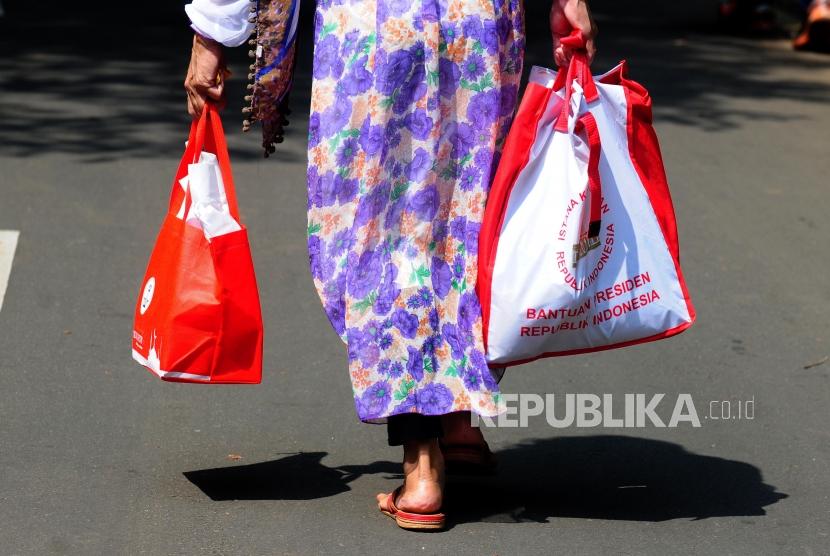 Warga berjalan membawa bingkisan usai menghadiri open house Presiden Joko Widodo di kawasan Kebun Raya Bogor, Kota Bogor, Jawa Barat, Jumat (15/6).