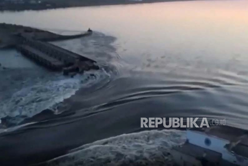 Tangkapan layar dari video yang dirilis oleh Kantor Kepresidenan Ukraina, air mengalir melalui di bendungan yang jebol di Kakhovka di Kakhovka, Ukraina, Selasa, (6/6/2023).