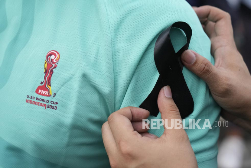  Seorang aktivis meletakkan pita hitam di bahu seorang teman saat unjuk rasa menentang pembatalan Piala Dunia FIFA U-20, di Jakarta, Jumat (31/3/2023).  Aksi tersebut sebagai bentuk duka cita atas dibatalkannya Indonesia sebagai tuan rumah Piala Dunia U-20.